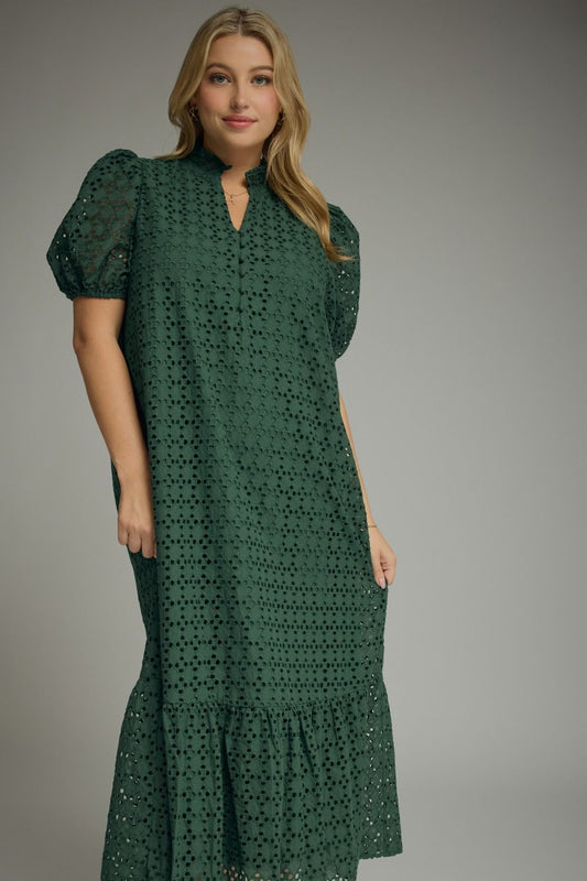 Woman wearing an Entro hunter green eyelet midi dress with puff sleeves, ruffled mock neckline, button front, ruffle hem, and side pockets.