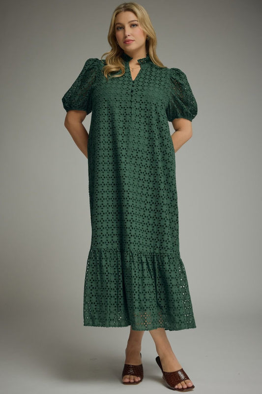 Woman wearing an Entro hunter green eyelet midi dress with puff sleeves, ruffled mock neckline, button front, ruffle hem, and side pockets.